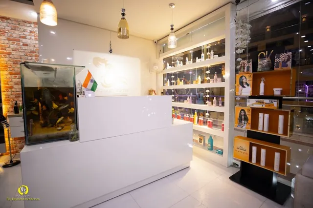 The reception desk at Glowup Studio, with a fish tank, an Indian flag, and shelves of hair-care product bottles and boxes on display.